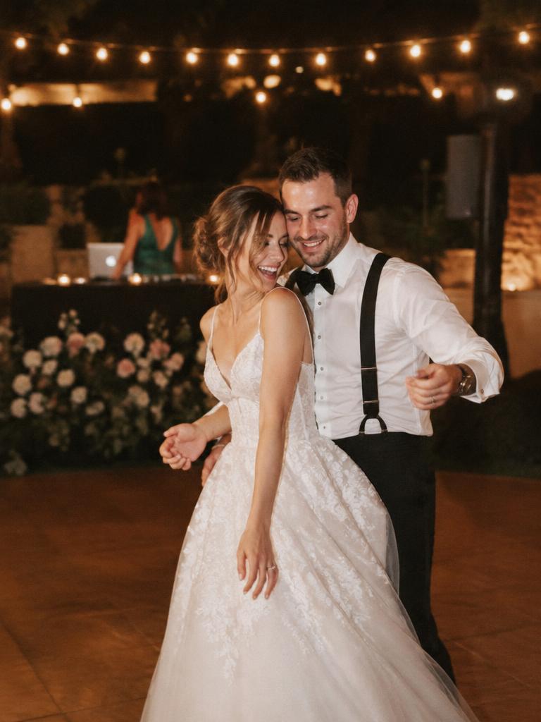 Bride and groom dancing under festoon lights with the DJ behind them