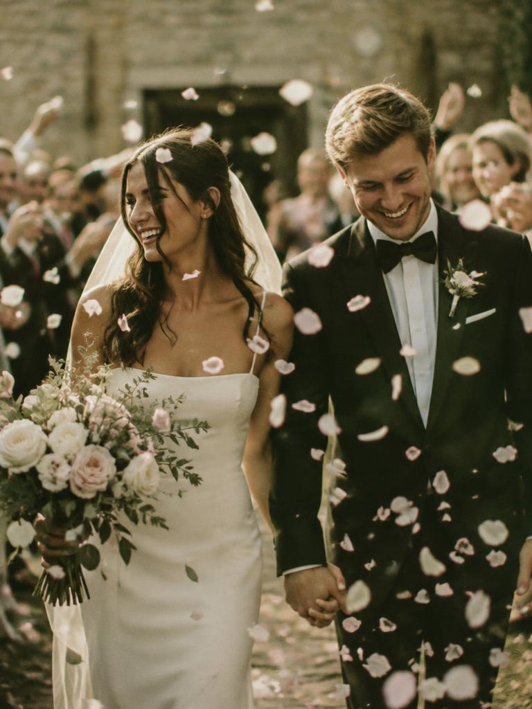 Newlyweds walking through a shower of petal confetti as guests cheer