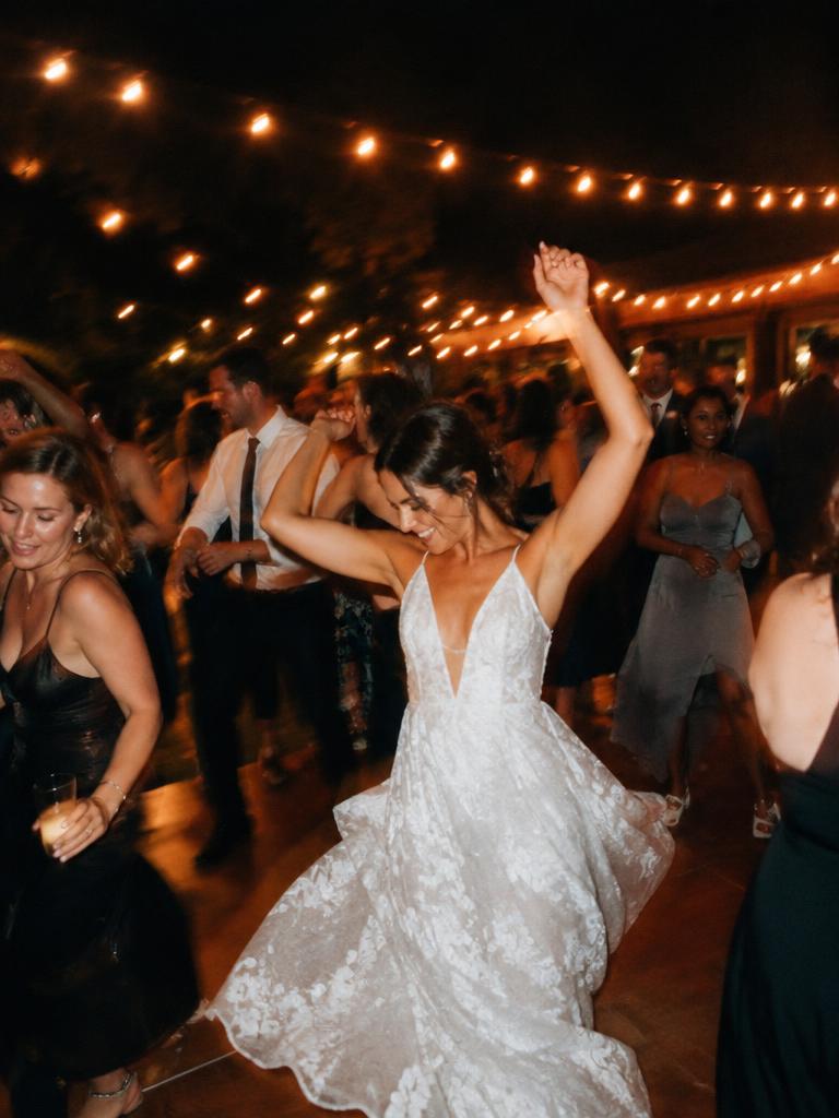 Bride dancing with her arms up on a packed dance floor